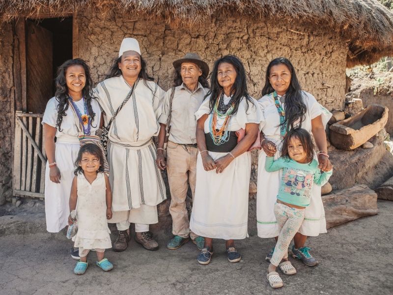 an-arhuaca-family-poses-in-front-of-their-house
