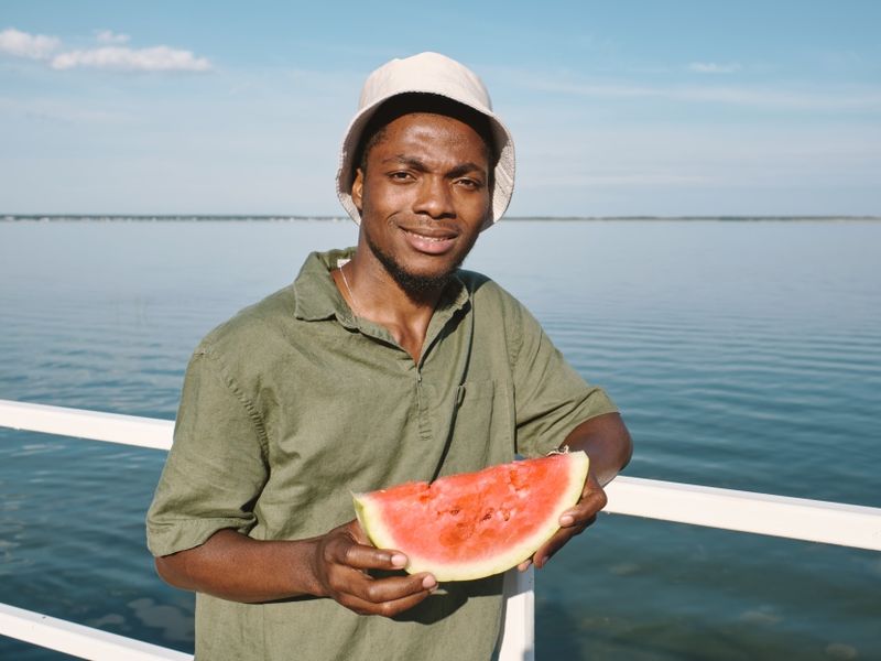 happy-guy-of-african-ethnicity-holding-slice-of-ju