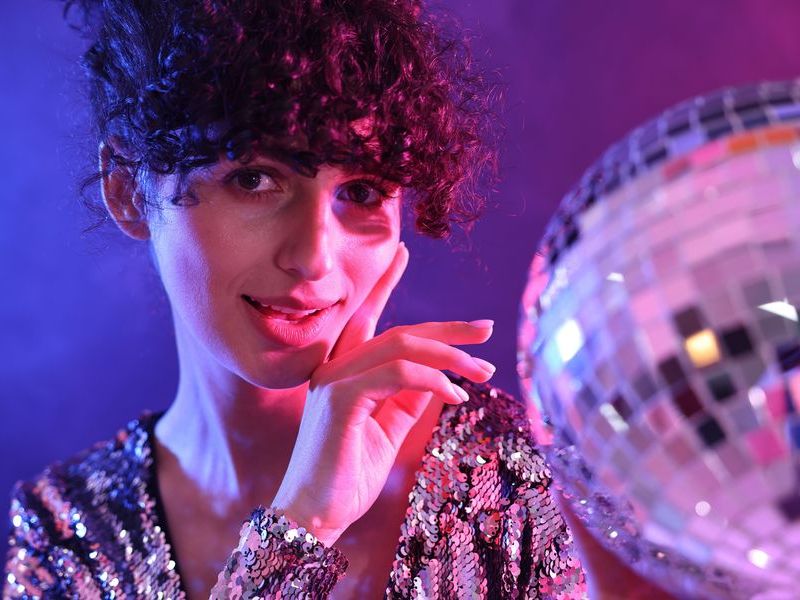 woman-with-disco-ball-in-colorful-studio-lighting-2026-04-08-22-22-36-utc